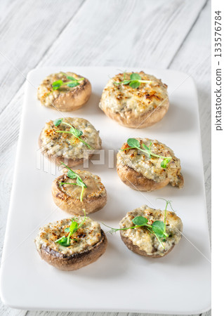 Melted blue cheese fills baked mushroom caps creating savory aroma on simple white plate Melted blue cheese fills baked mushroom caps creating savory aroma on simple white plate 133576784
