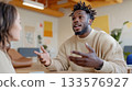 Black man speaking confidently during a strategy meeting with a white female colleague in a minimalist office 133576927