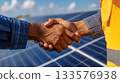 Business professional shaking hands with solar executive in front of solar panels, symbolizing a renewable energy finance partnership 133576938