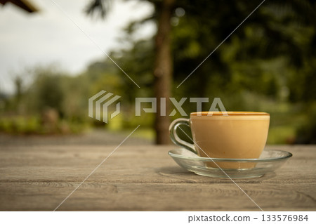 Coffee on a table with greenery behind it Coffee on a table with greenery behind it 133576984