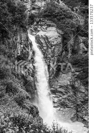 Wild alpine waterfall on Schlatenbach mountain stream. Gschloesstal Valley, Hohe Tauern National Park, East Tyrol, Austrian Alps. Black and white image. 133578237