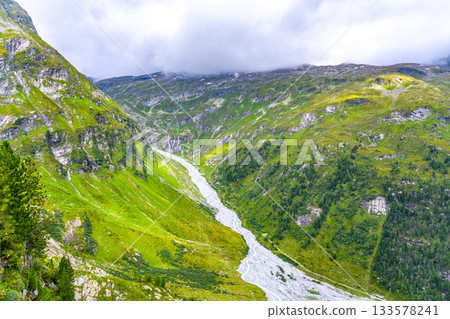 Narrow twisted rocky stream in alpine valley. Gschlosstal Valley, Hohe Tauern National Park, East Tyrol, Austrian Alps Narrow twisted rocky stream in alpine valley. Gschlosstal Valley, Hohe Tauern National Park, East Tyrol, Austrian Alps 133578241