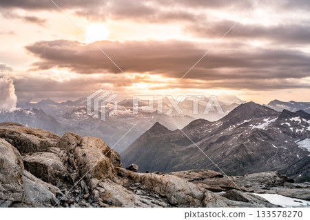 Rocky alpine mountains morning panorama. Cloudy sunrise on summer day. Grossglockner Mountain, Hohe Tauern National Park, Austrian Alps Rocky alpine mountains morning panorama. Cloudy sunrise on summer day. Grossglockner Mountain, Hohe Tauern National Park, Austrian Alps 133578270