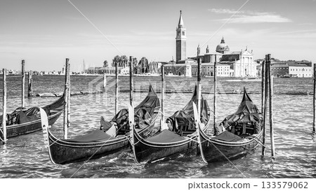 Moored gondolas at St. Mark Square with Church of San Giorgio Maggiore on background. Venice, Italy. Black and white image. 133579062