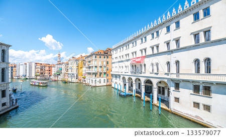On a sunny day in Venice, colorful buildings line the Canal Grande, with boats gliding along the tranquil waters. This historic waterway is bustling with life and rich in culture. On a sunny day in Venice, colorful buildings line the Canal Grande, with boats gliding along the tranquil waters. This historic waterway is bustling with life and rich in culture. 133579077