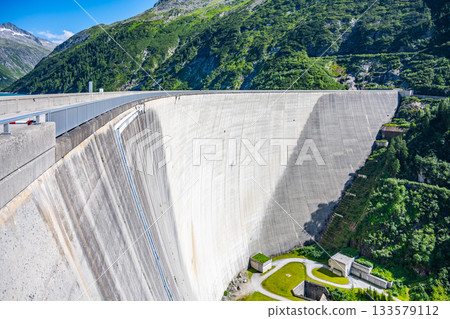 Huge concrete apline dam on sunny summer day. Zillergrundl Speicher, Zillertal Alps, Austria Huge concrete apline dam on sunny summer day. Zillergrundl Speicher, Zillertal Alps, Austria 133579112