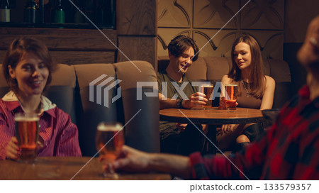 Friends enjoying beer together in relaxed pub corner 133579357