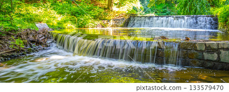 Small double waterfall on the forest stream. Gaden stone sluice in tranquil forest mood. 133579470