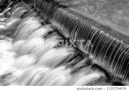 Small waterfall on the forest stream. Gaden stone sluice in tranquil forest mood. Black and white image. Small waterfall on the forest stream. Gaden stone sluice in tranquil forest mood. Black and white image. 133579474