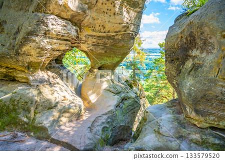 Discover the unique sandstone formations of Prihrazy Rocks in Bohemian Paradise, Czechia, showcasing natural arches and scenic views in a tranquil outdoor setting. 133579520