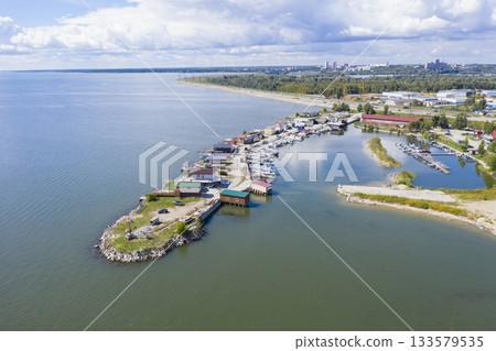 Aerial view of the cape and harbor with boats on bay of river with high-rise buildings on horizon 133579535