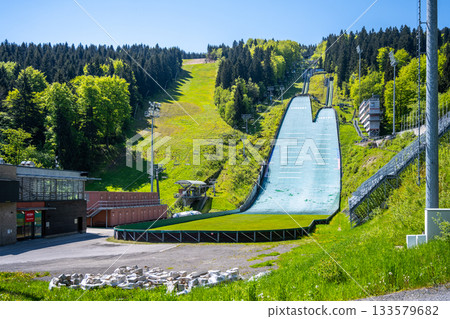 Jested ski jumps in Liberec, Czechia, provide a striking view against lush green hills. The facility is ready for summer training, showcasing its pristine condition and athletic spirit. Jested ski jumps in Liberec, Czechia, provide a striking view against lush green hills. The facility is ready for summer training, showcasing its pristine condition and athletic spirit. 133579682