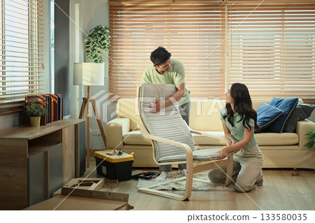 Young couple assembling new armchair together at home, teamwork in DIY furniture project 133580035