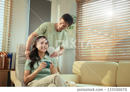 Loving couple relaxing at home, man giving gentle shoulder massage to his smiling partner 133580078