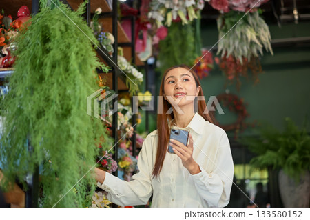 Owner small business managing flower stock with a smartphone Owner small business managing flower stock with a smartphone 133580152