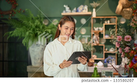 Florist woman business owner managing flower stock with a digital tablet 133580207