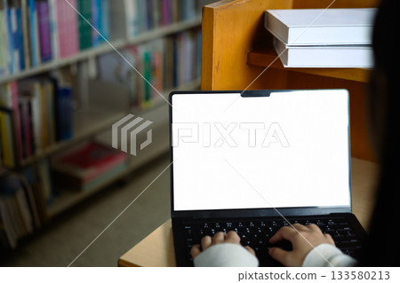 Hands holding mockup laptop in library 133580213
