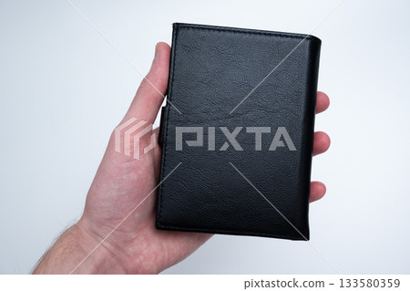 Black Leather Wallet in Male Hand on Light Black Leather Wallet in Male Hand on Light 133580359