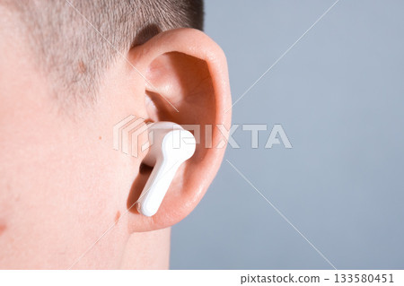 Inserting White Earbud into Ear 133580451