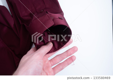 Human hand smoothing maroon shirt fabric Human hand smoothing maroon shirt fabric 133580469