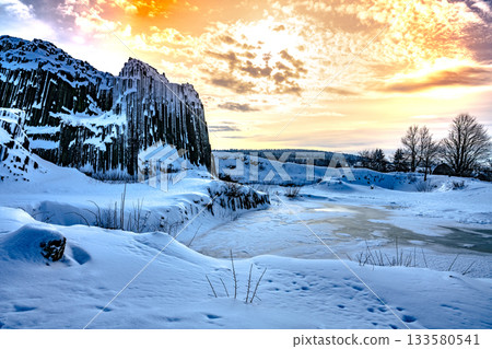 Panska skala - rock formation of pentagonal and hexagonal basalt columns. Looks like giant organ pipes. Covered by snow and ice in winter time. Kamenicky Senov, Czech Republic. 133580541