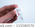 Hand Removing White Earbud from Case 133580570