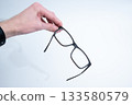 Hand Holding Glasses Above Black Case 133580579