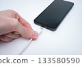 Charging smartphone with cable in hand close-up for digital technology concept 133580590
