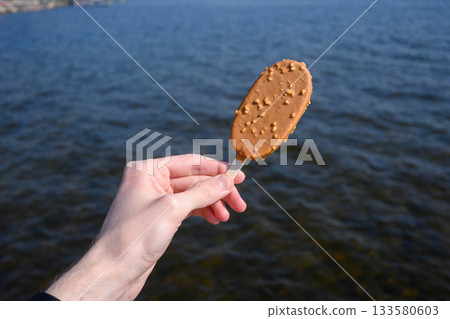 Delicious Chocolate Nut Ice Cream by Lake in Summer Delicious Chocolate Nut Ice Cream by Lake in Summer 133580603