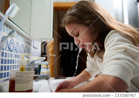 Young Girl Washing Hands At Sink In Bathroom, Water Splashing, Personal Hygiene Moment 133580767