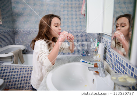 Young Girl Washing Hands At Bathroom Sink In Mirror Image 133580787