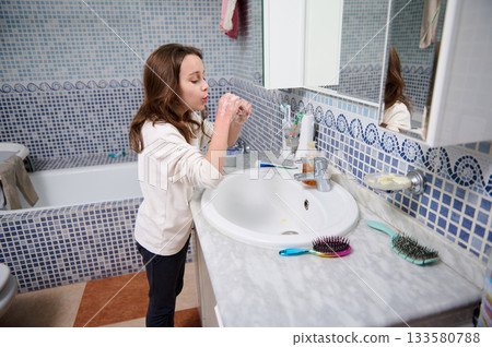 Girl Washing Hands At Bathroom Sink With Mirror And Blue Mosaic Tiles Girl Washing Hands At Bathroom Sink With Mirror And Blue Mosaic Tiles 133580788
