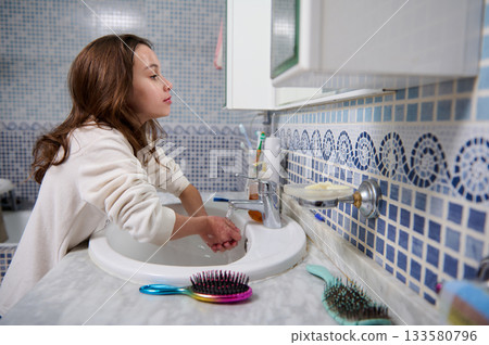 Young Girl Washing Hands At Bathroom Sink In Blue Mosaic Tile 133580796