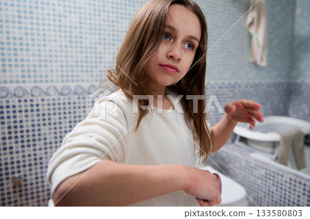 Young Girl In White Sweater Looking Thoughtful In A Tiled Bathroom 133580803