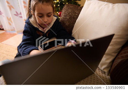 Child Using Laptop And Phone On Couch Near Christmas Tree 133580901