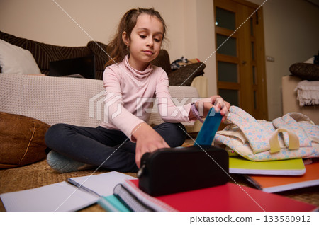 Girl Packing School Supplies at Home, Focused on Pencil Case and Notebooks Girl Packing School Supplies at Home, Focused on Pencil Case and Notebooks 133580912