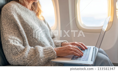 Woman working remotely on laptop while sitting by airplane window, showcasing travel lifestyle and productivity in a unique environment Woman working remotely on laptop while sitting by airplane window, showcasing travel lifestyle and productivity in a unique environment 133581347