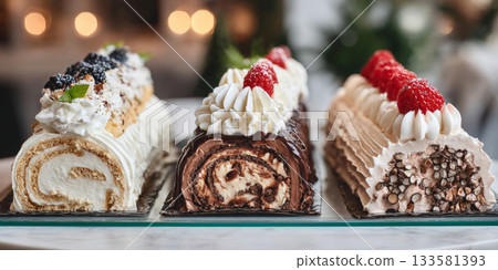 Three distinct styles of buche de noel arranged elegantly on a glass display table with luxurious patisserie lighting Three distinct styles of buche de noel arranged elegantly on a glass display table with luxurious patisserie lighting 133581393