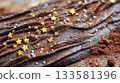 Macro photo of textured chocolate bark decoration on buche de noel with edible gold stars and cocoa powder for festive holiday dessert 133581396