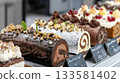 Assorted buche de noel flavors displayed on a bakery counter, showcasing festive holiday desserts in bright ambient light with modern presentation 133581402