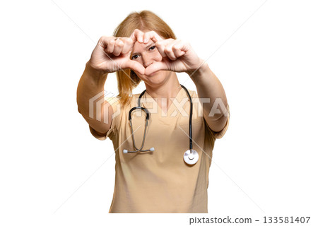 A female doctor, a healthcare worker, shows a heart with both hands extended forward, at eye level. A female doctor, a healthcare worker, shows a heart with both hands extended forward, at eye level. 133581407