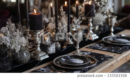 Antique silver goblets and celestial-themed plates on a dark velvet table runner, creating a moody Gothic Christmas ambiance 133581508
