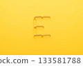 Vitamin E capsules with alphabet letter E on yellow background. Oil Softgel capsule uses for nutritional supplement, hair serum, skincare product and cosmetic ingredient. 133581788