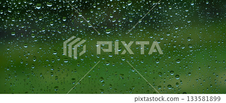 A rainy day window view. Rain drops on window. Condensed rain drop on the car glass window on a rainy day. Dew moisture condensation on wet mirror background. Fresh weather. Water raindrop bg 133581899