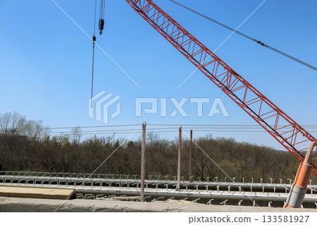 Construction workers use crane to lift materials at during concrete bridge reconstruction 133581927