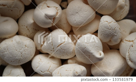 Dry brittle cracked meringues with a crispy sugar crust as a white sweet background of homemade sweets for tea drinking, close-up of a group of light meringues as a banner texture of sweets Dry brittle cracked meringues with a crispy sugar crust as a white sweet background of homemade sweets for tea drinking, close-up of a group of light meringues as a banner texture of sweets 133581979