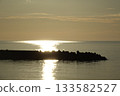 The light of the setting sun reflected on the calm sea surface 133582527