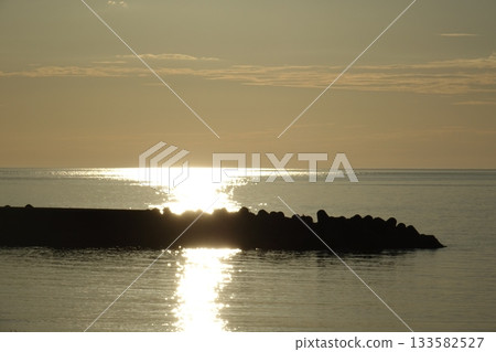 夕陽的餘暉灑在平靜的海面上。 夕陽的餘暉灑在平靜的海面上。 133582527