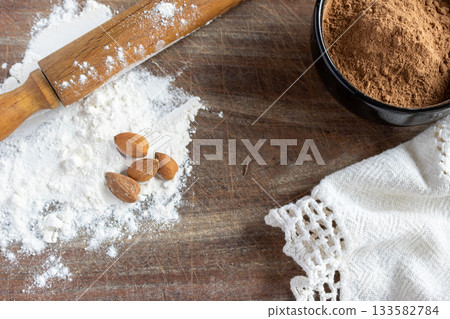 Baking still life, cocoa powder, white flour, walnuts and rolling pin on rustic wooden surface. Copy space 133582784