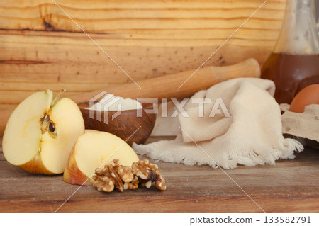 Rustic wooden table with baking ingredients for apple walnut desserts, sliced apples, walnuts, flour, eggs, oil, rolling pin and towel ready for homemade pies and pastries Rustic wooden table with baking ingredients for apple walnut desserts, sliced apples, walnuts, flour, eggs, oil, rolling pin and towel ready for homemade pies and pastries 133582791